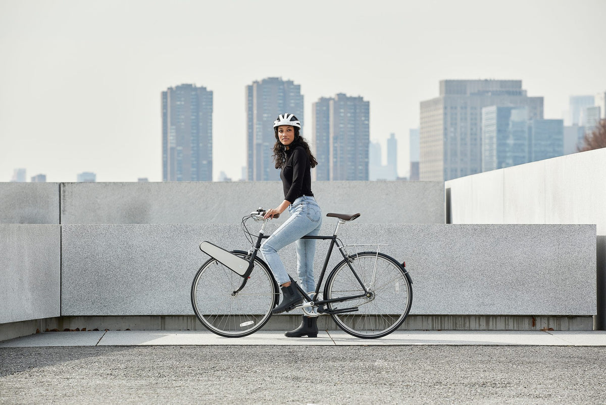 A rider with CLIP on her front wheel on a rooftop, with the Manhattan skyline behind