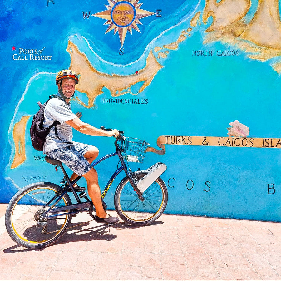 Steve riding his CLIP-equipped bike past a Turks and Caicos map mural