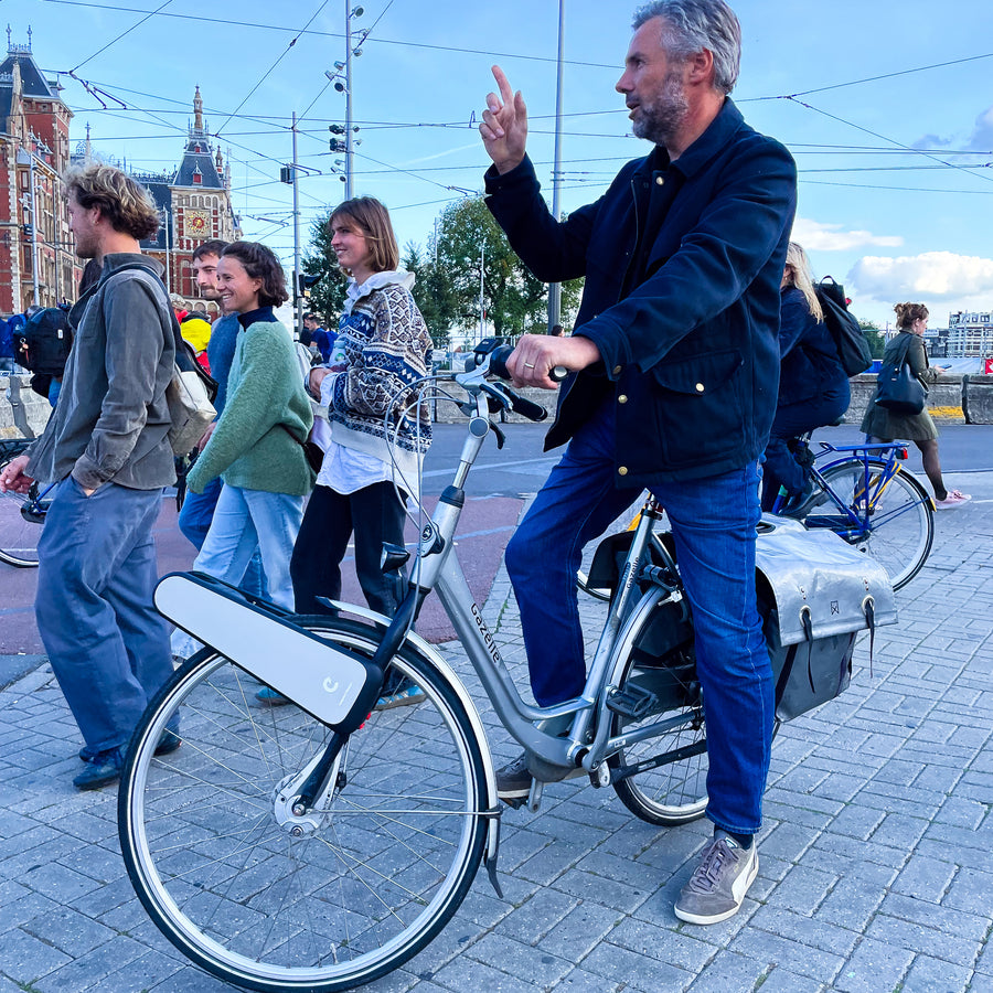 A rider on a CLIP bike waves in a busy square