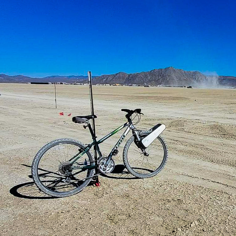 A bike fitted with CLIP standing on the desert floor at Black Rock, mountains behind