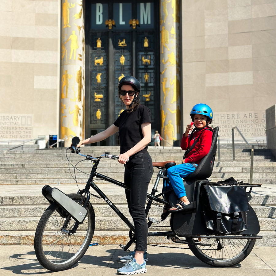 A parent with a child seat and CLIP in front of a building