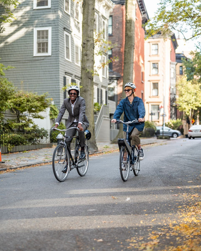 Two riders on a tree-lined street