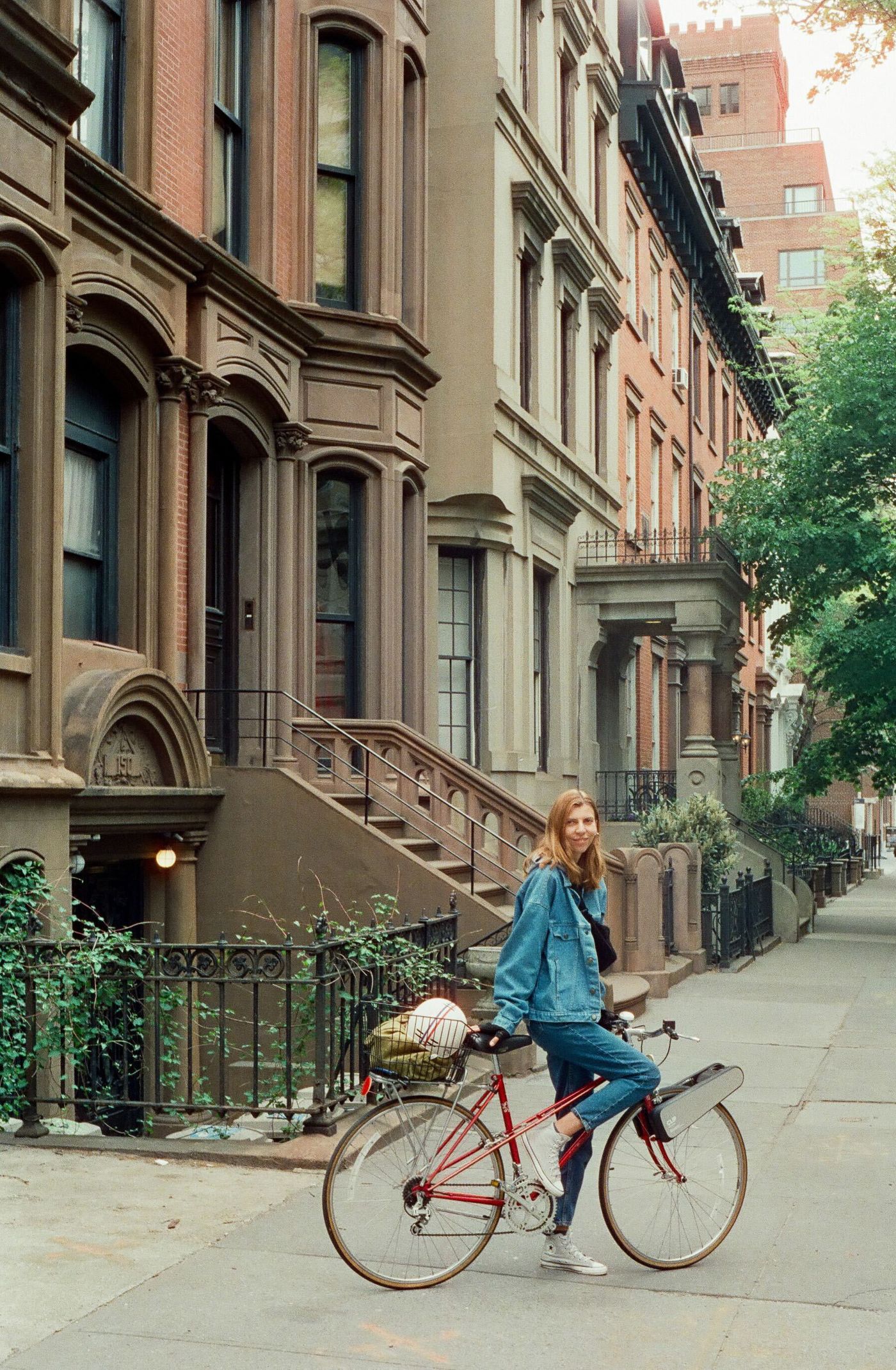 A rider on a red city bike with CLIP, on a brownstone street in Brooklyn